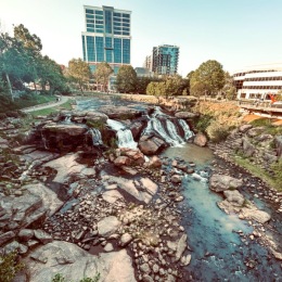 river with waterfalls and cityscape in background